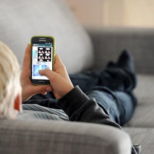 Junge liegt mit Smartphone auf dem Sofa