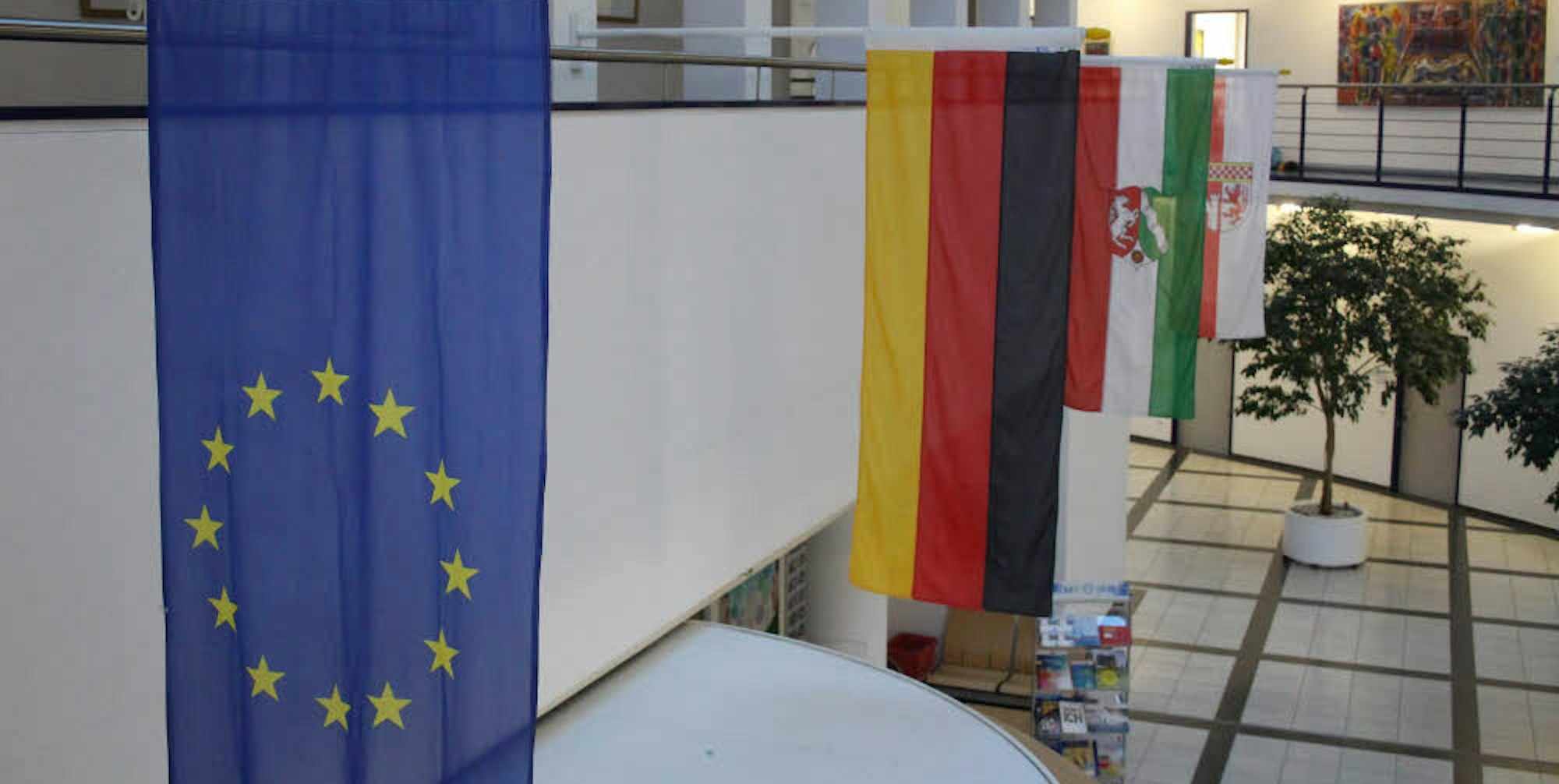 Im Foyer in Gummersbach hängt die Europafahne neben der deutschen, der von Nordrhein-Westfalen und der des Oberbergischen Kreises.