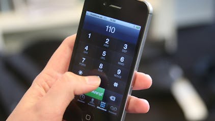 Eine Frau wählt mit ihrem Handy den Notruf 110.