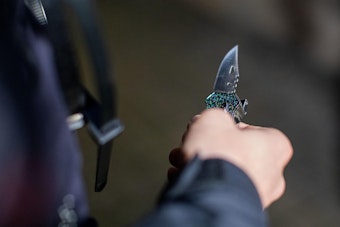 Ein Polizist hält ein sichergestelltes Messer in der Hand.