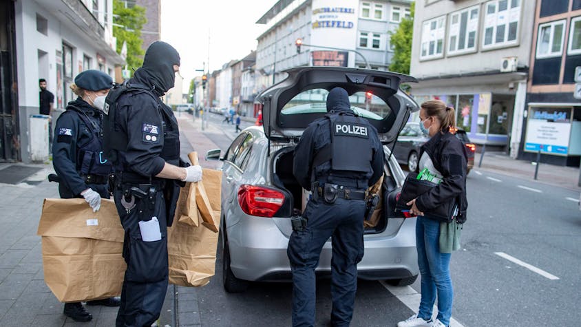 Polizisten bringen in Tüten sichergestelltes Beweismittel zu einem Auto.