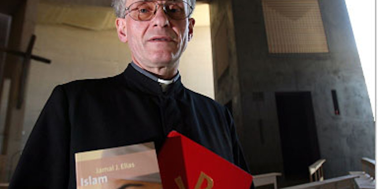 Der katholische Pfarrer Franz Meurer in der St. Theodor-Kirche in Köln-Vingst mit einer Bibel und einem Buch über den Islam in der Hand.