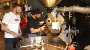 Zwei Männer rösten Kaffeebohnen in einer Maschine