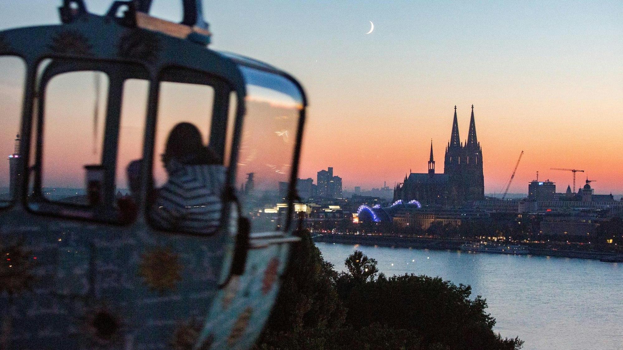 Gondel einer Seilbahn mit Blick auf Rhein und Dom bei Sonnenuntergang