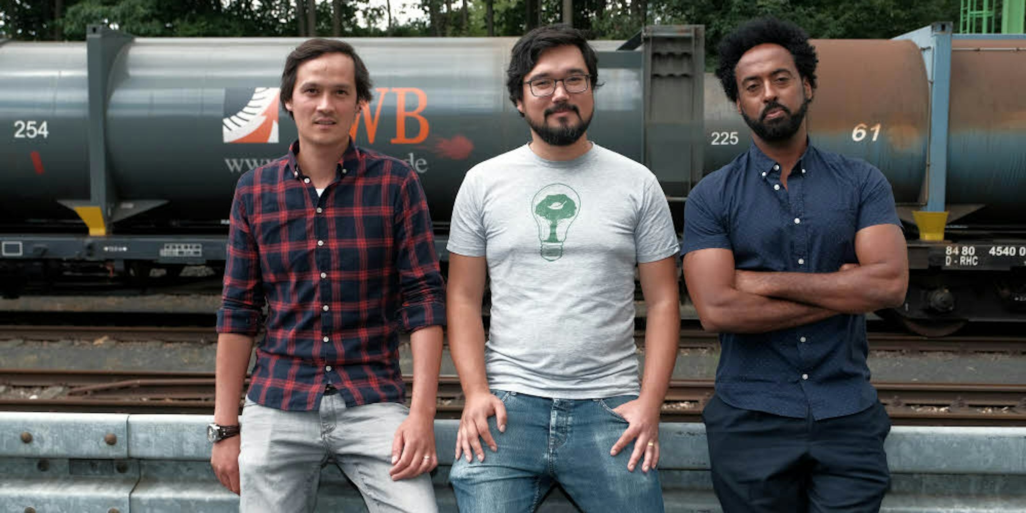 Drei Kölner Start-up-Unternehmer: Thomas Chiang, Kalie Cheng und Abiye Dagnew vor den Müllzügen der AWB