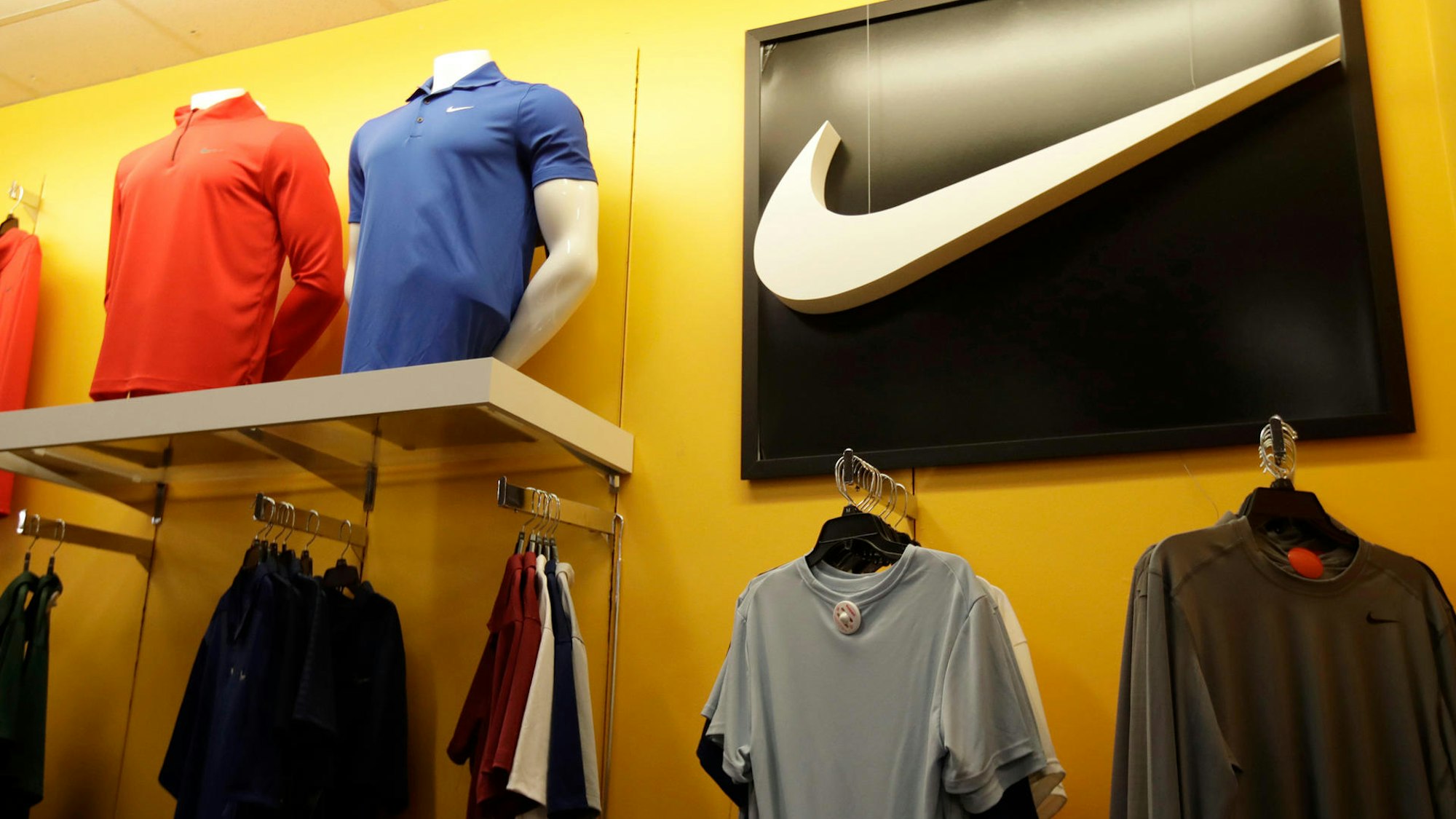 T-Shirts an Kleiderbügeln und Schaufensterpuppen, darüber das Nike-Logo