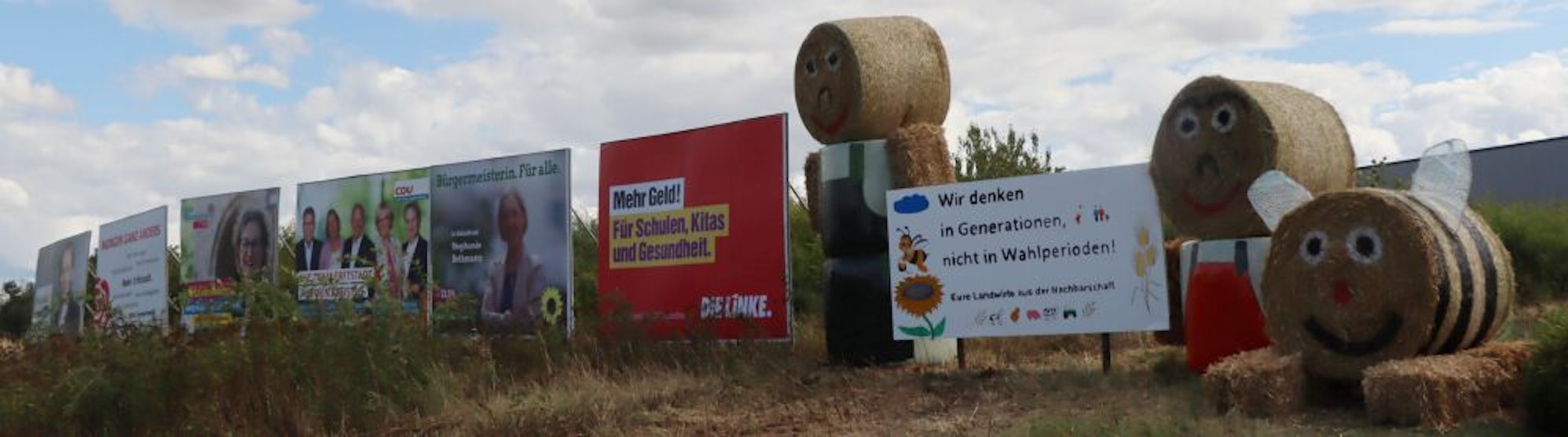 Neben den Wahlplakaten der Parteien haben die Bauern in Erftstadt-Lechenich große Strohfiguren und eine Schrifttafel aufgestellt.