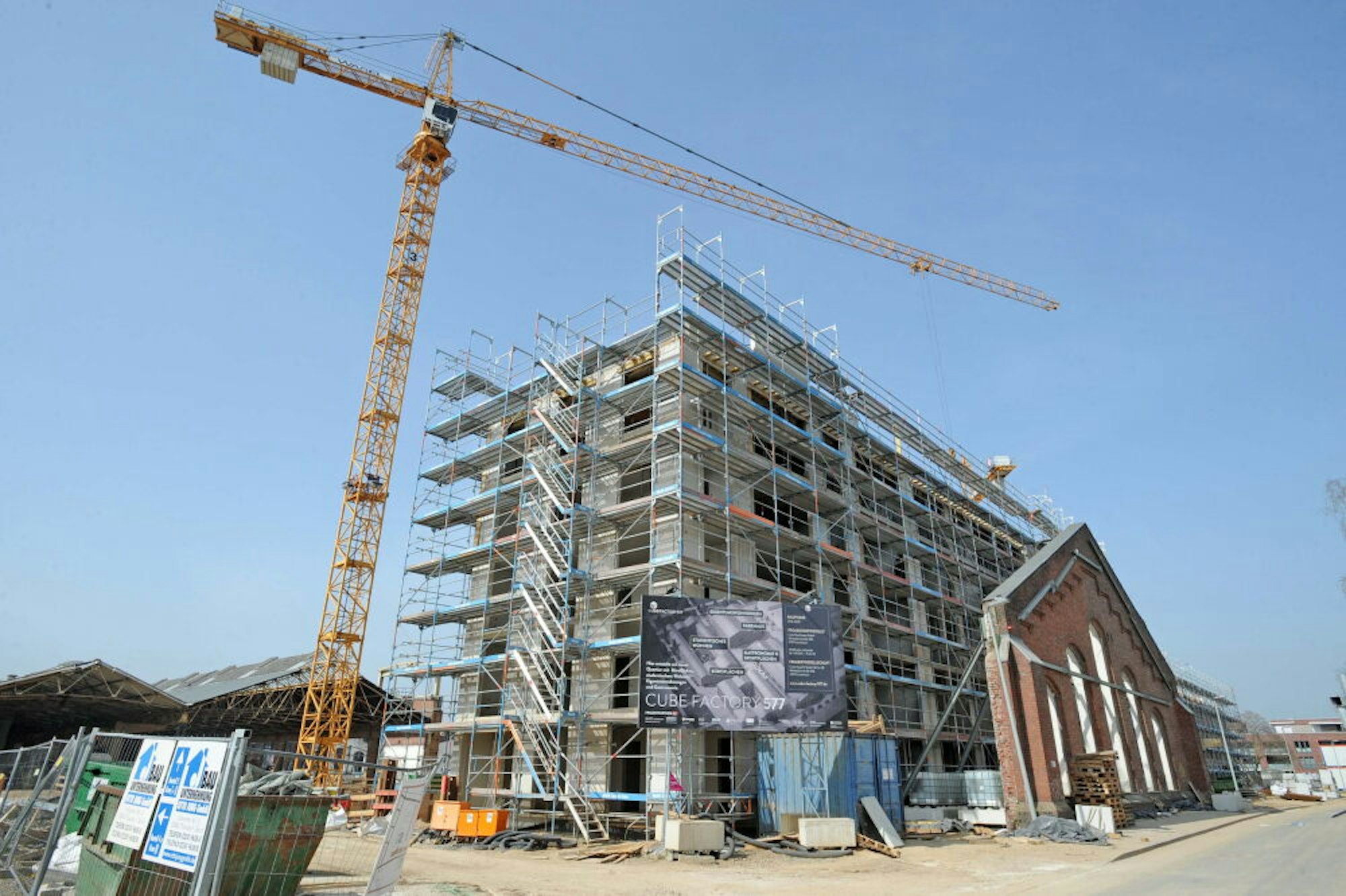 Ein Wohnhaus des Großprojektes Cube Factory 577 wächst hinter dem alten Fassadenteil der Eisenbahn-Halle zügig in die Höhe.