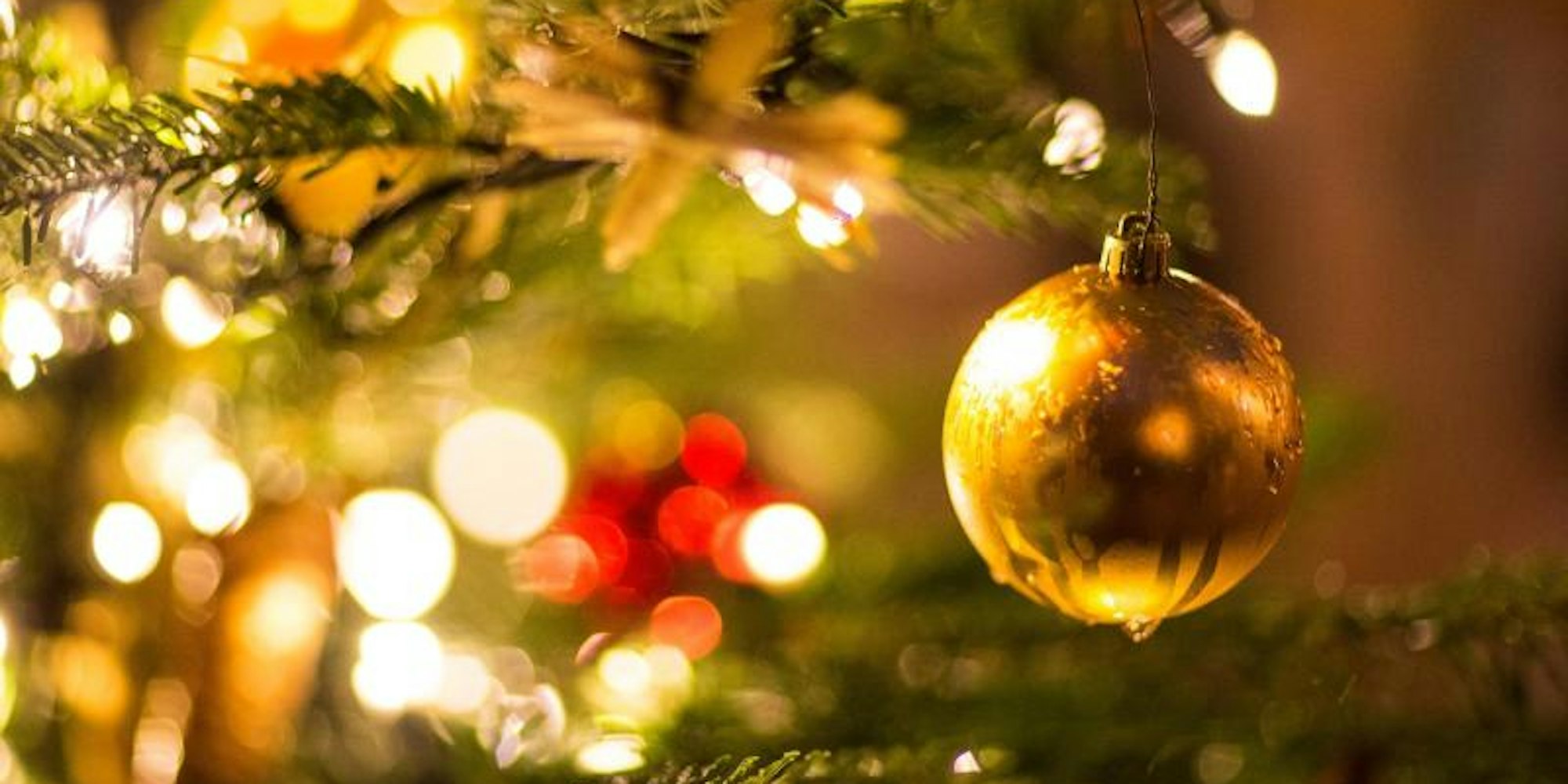 Eine goldene Kugel hängt an einem Weihnachtsbaum. Der Infektiologe Bernd Salzberger warnt davor, dass Weihnachts-Treffen die Ausbreitung des Coronavirus verstärken könnten.