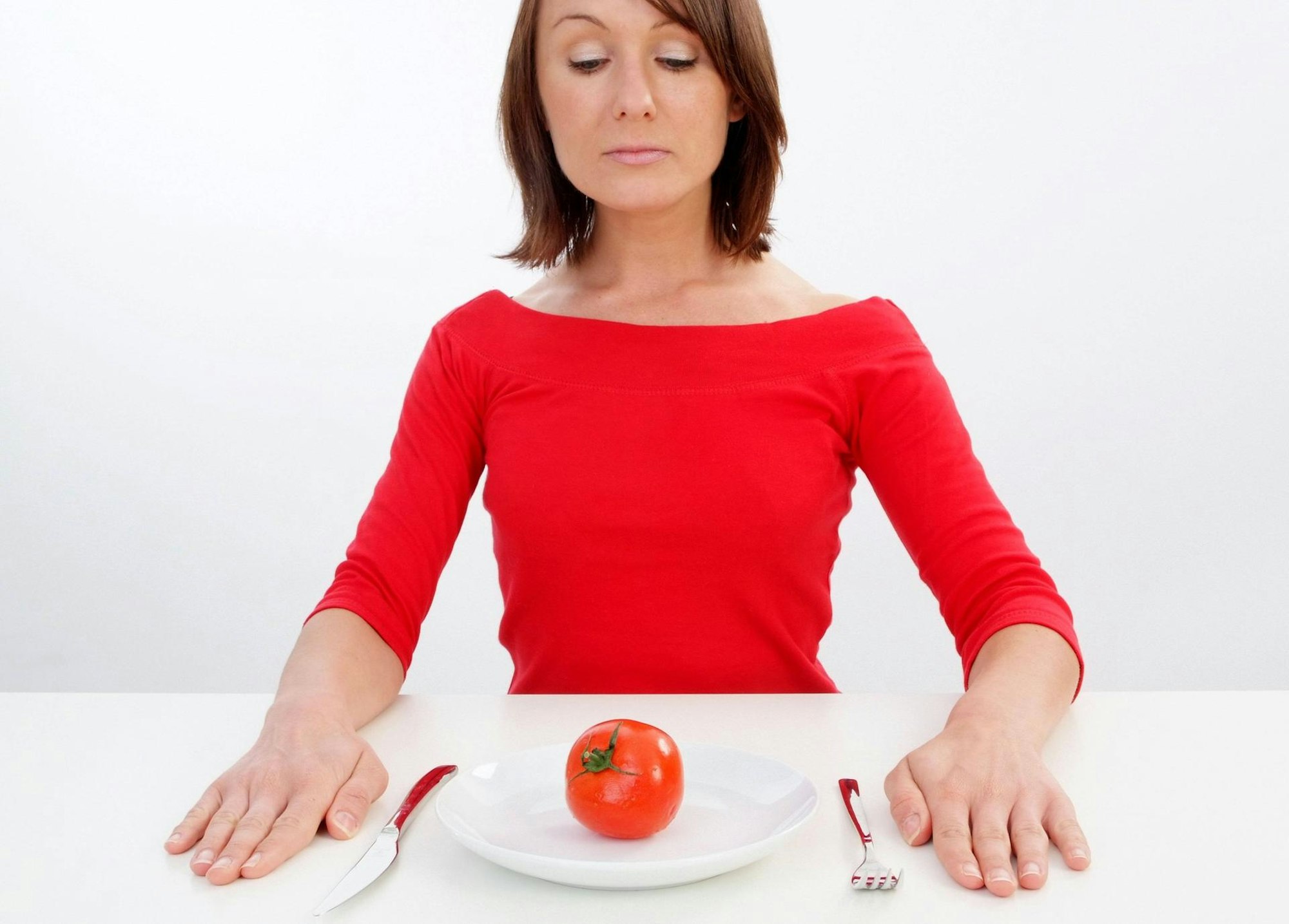 Orthorexie Clean Eating Frau isst Tomate Teller leer imago
