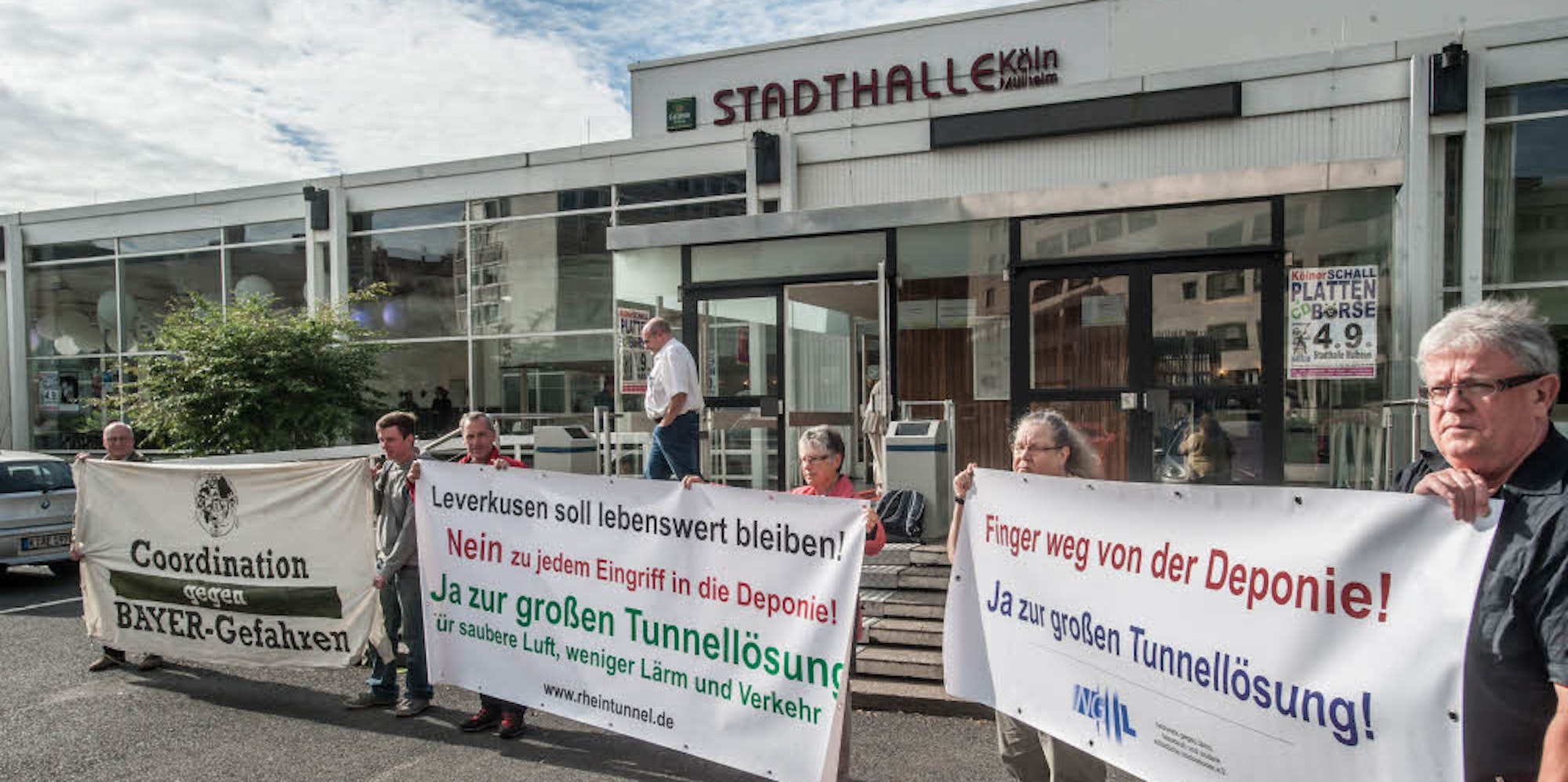 Mitglieder Leverkusener Bürgerinitiativen rollten vor Beginn der Veranstaltung an Mülheimer Stadthalle ihre Plakate aus.