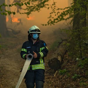 Ein Feuerwehrmann versucht inmitten lodernder Feuer in Gummersbach zu löschen.