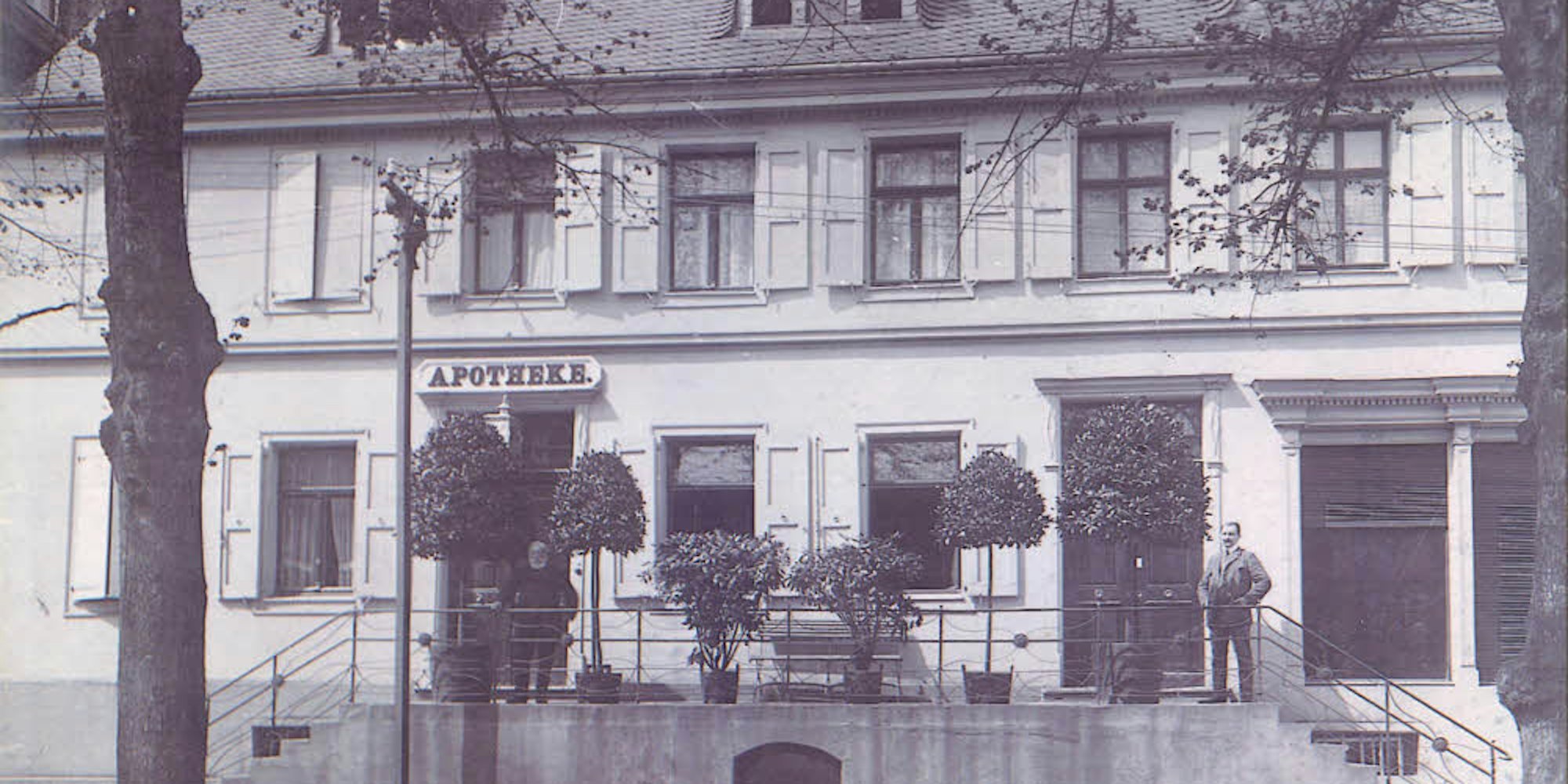 Die erste Apotheke in Eitorf mit Apotheker Julius Schulz (links zwischen den Bäumen), etwa im Jahr 1900.