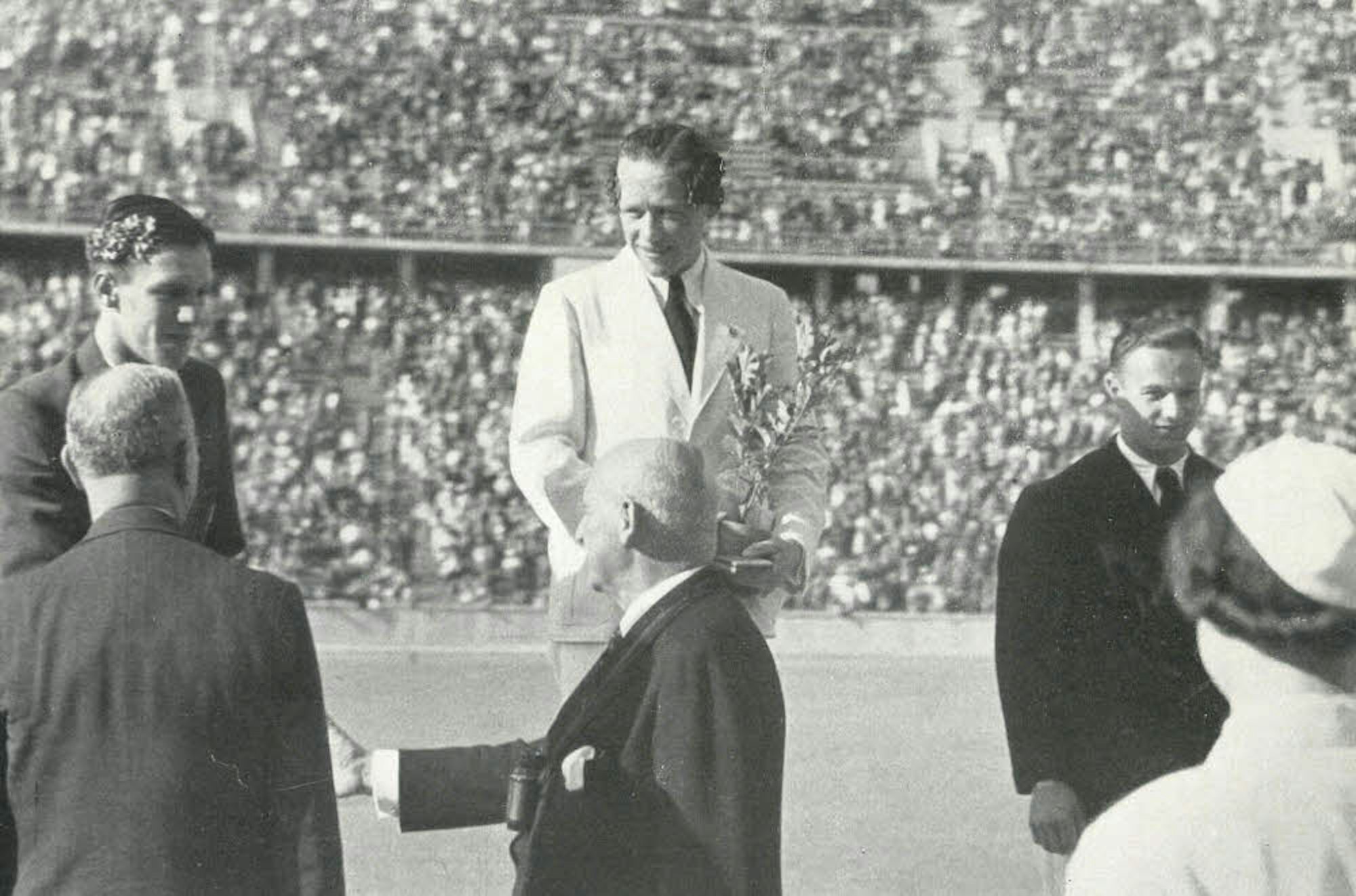 Toni Merkens (Mitte) bei der Siegerehrung im Berliner Olympiastadion. In der Hand hält er den Eichen-Setzling, den er zusätzlich zur Goldmedaille überreicht bekam.