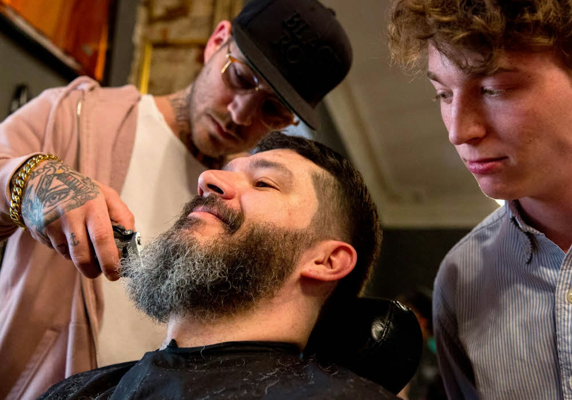 Barbier Felix Hohleich rasiert unter neidischen Blicken des Autors einen Kunden.
