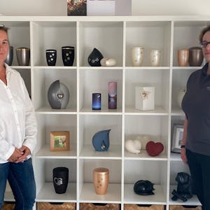 Rosengarten-Mitarbeiterinnen Sonja Hesselmann (l.) und Bianca Balerio-Hülsmann vor einer Auswahl an Urnen und Erinnerungsstücken.