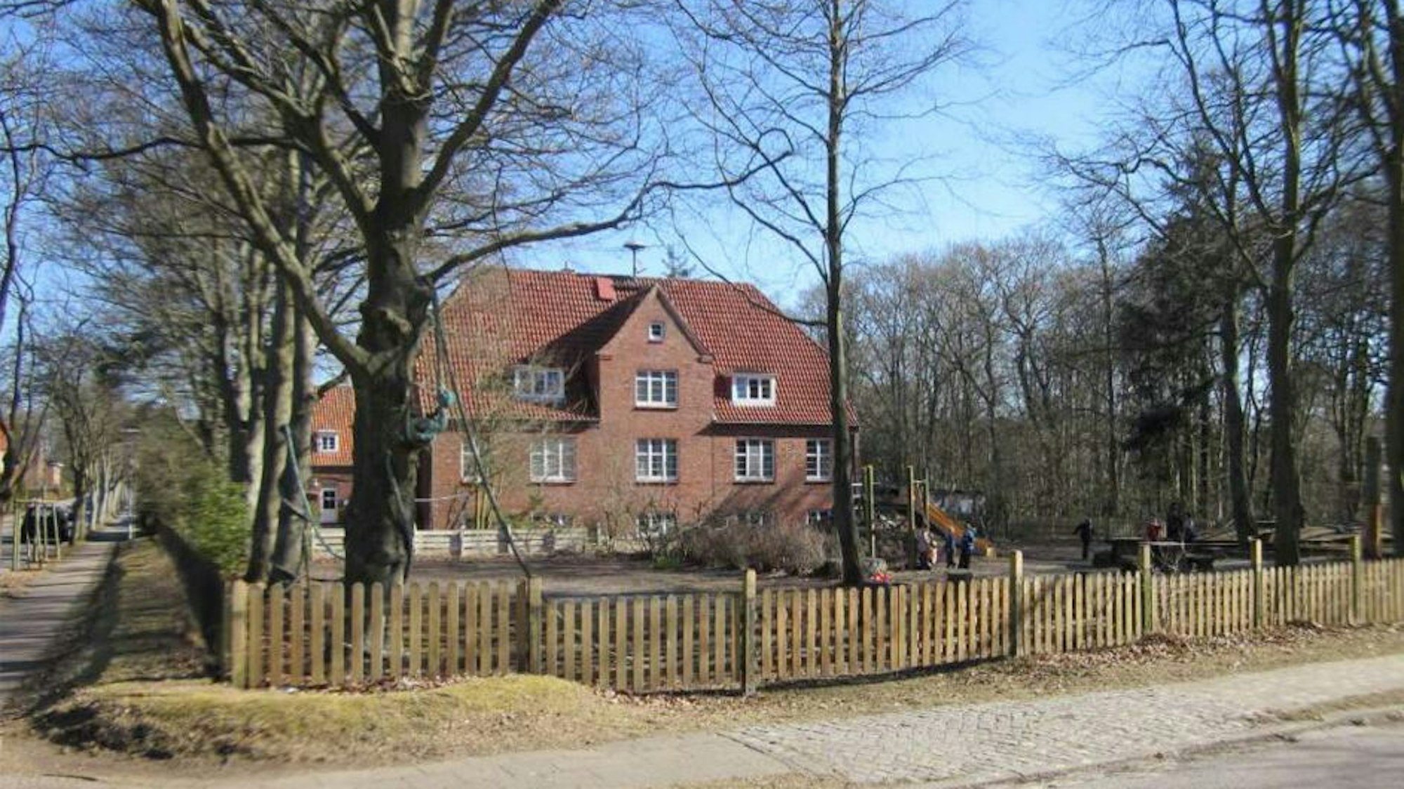 Ein Haus aus rotem Backstein mit umzäunten Grundstück.