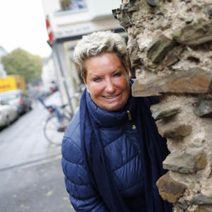 Marita Köllner vor einem Stück Römermauer, das mitten im Veedel steht.