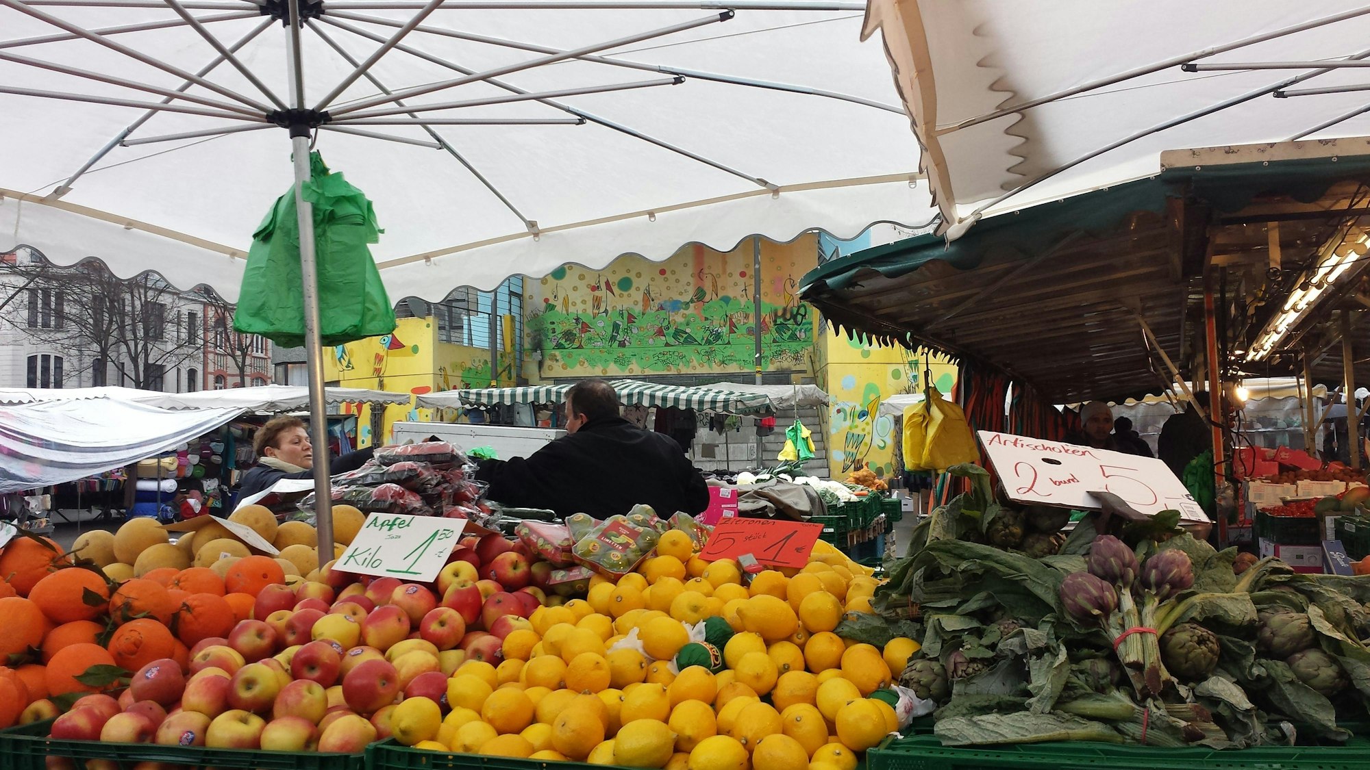 Ein Marktstand mit frischen Äfpeln, Zitronen und Artischocken.