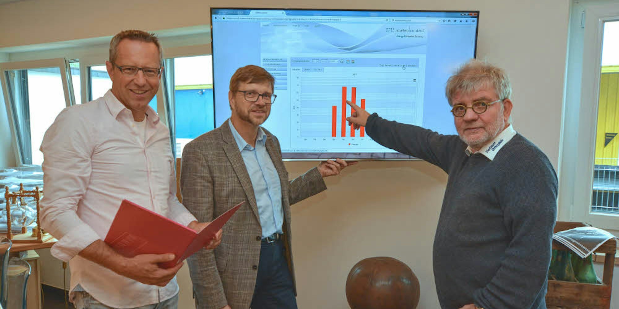 Auf dem Bildschirm kann Peter Vierbaum (r.) mit Guido Wendeler (l.) und Thomas Willmer von der EGBL, die Leistungsfähigkeit der Anlage verfolgen, die die Energiegenossenschaft auf dem Dach seiner Halle installiert hat.