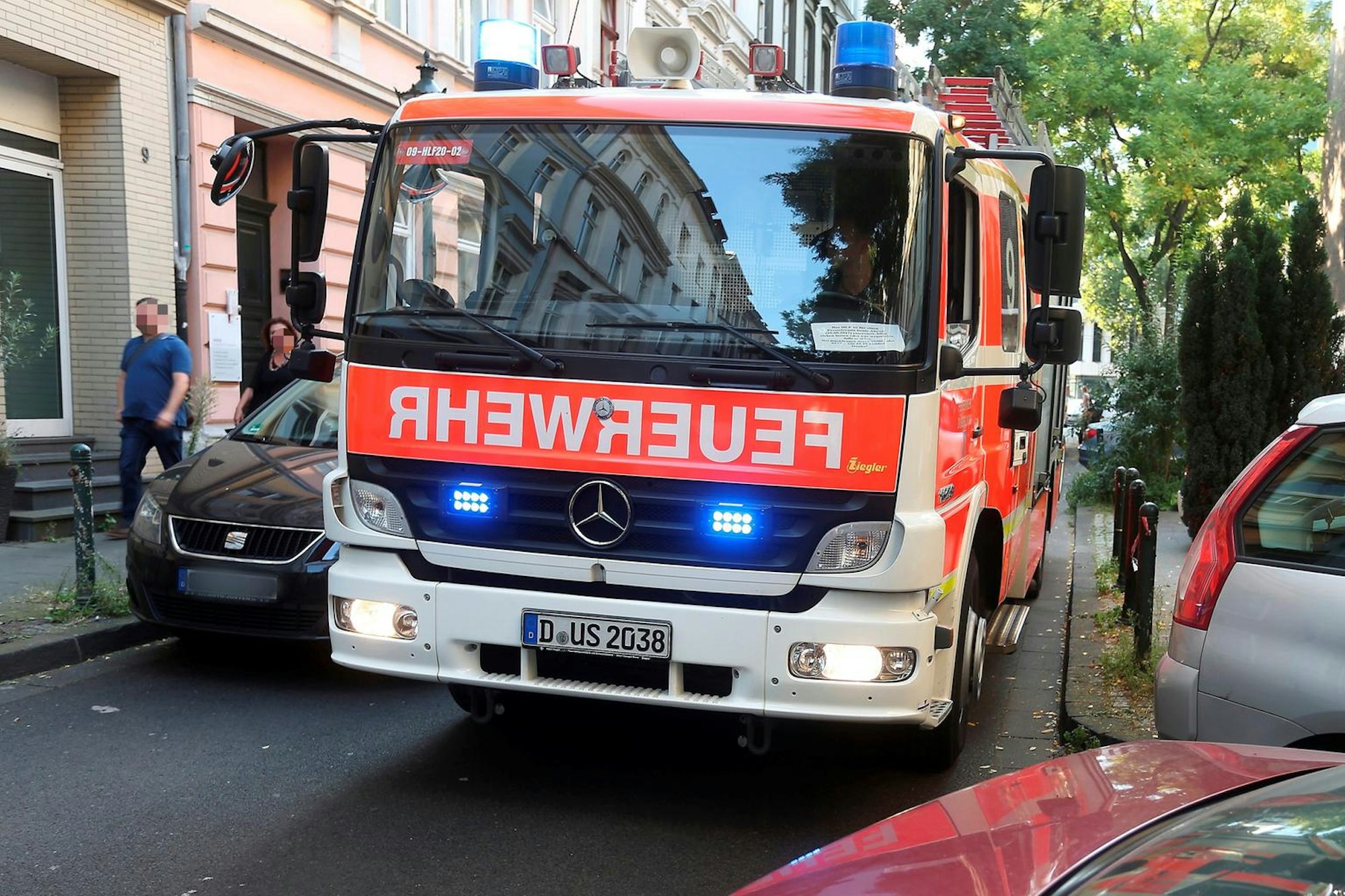 Ein Düsseldorfer Feuerwehrauto versucht mit Blaulicht durch eine enge Straße zu fahren.