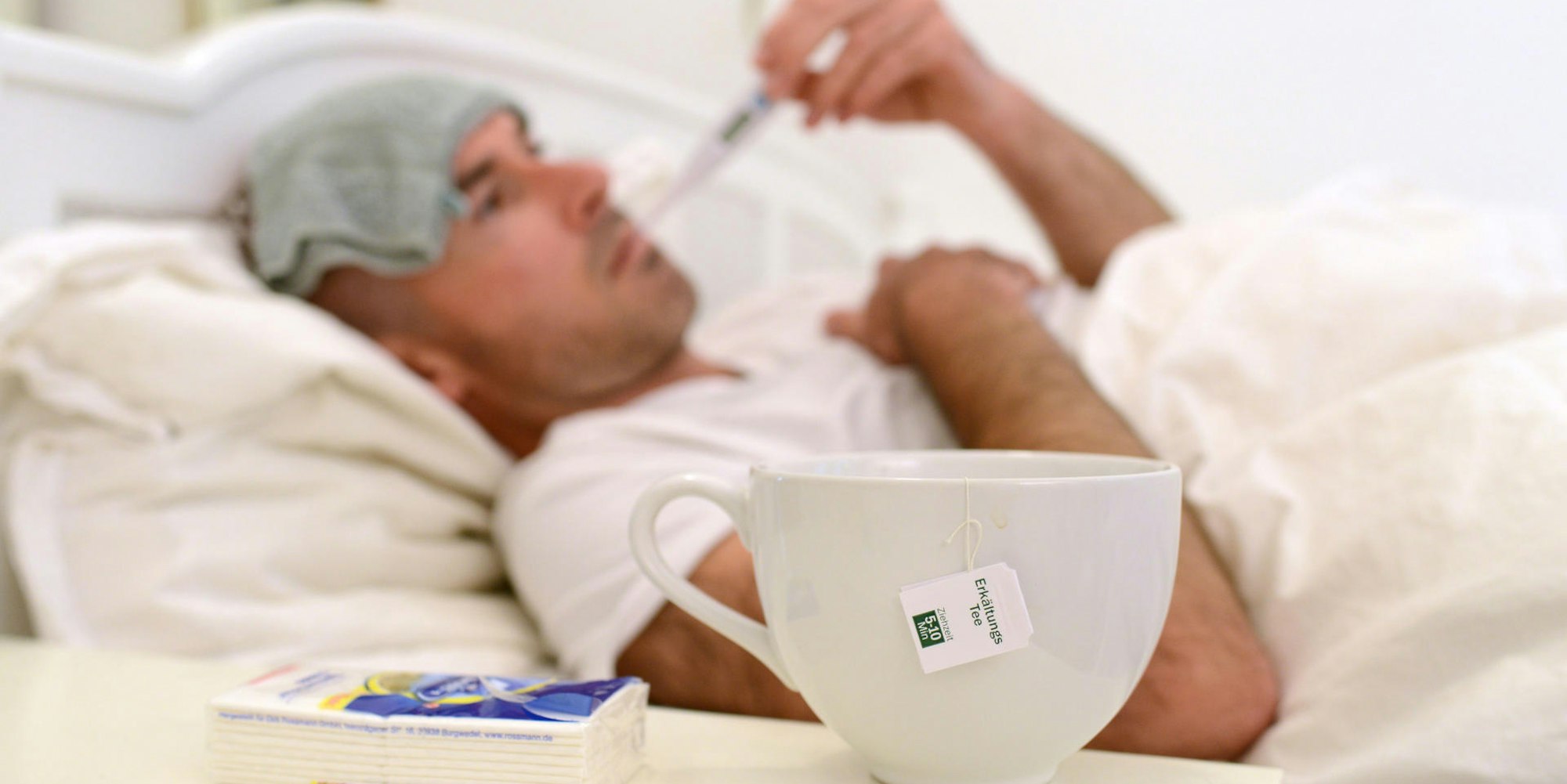 Mann liegt kranj mit Grippe oder Erkältung im Bett dpa