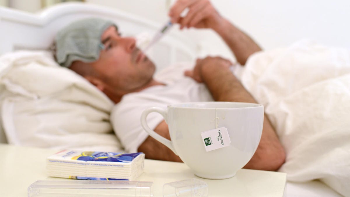 Mann liegt kranj mit Grippe oder Erkältung im Bett dpa