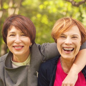 Zwei Frauen mittleren Alters lachen miteinander.