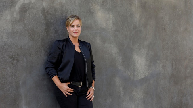 Die Grünen-Politikerin Mona Neubaur lehnt an einer Wand