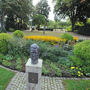 Die Büste von Seilbahn-Pionier Julius Pohlig steht neben dem Blumen-Pavillon (links) im Stadtpark an der Kirchstraße, der unter die Räder zu kommen droht.