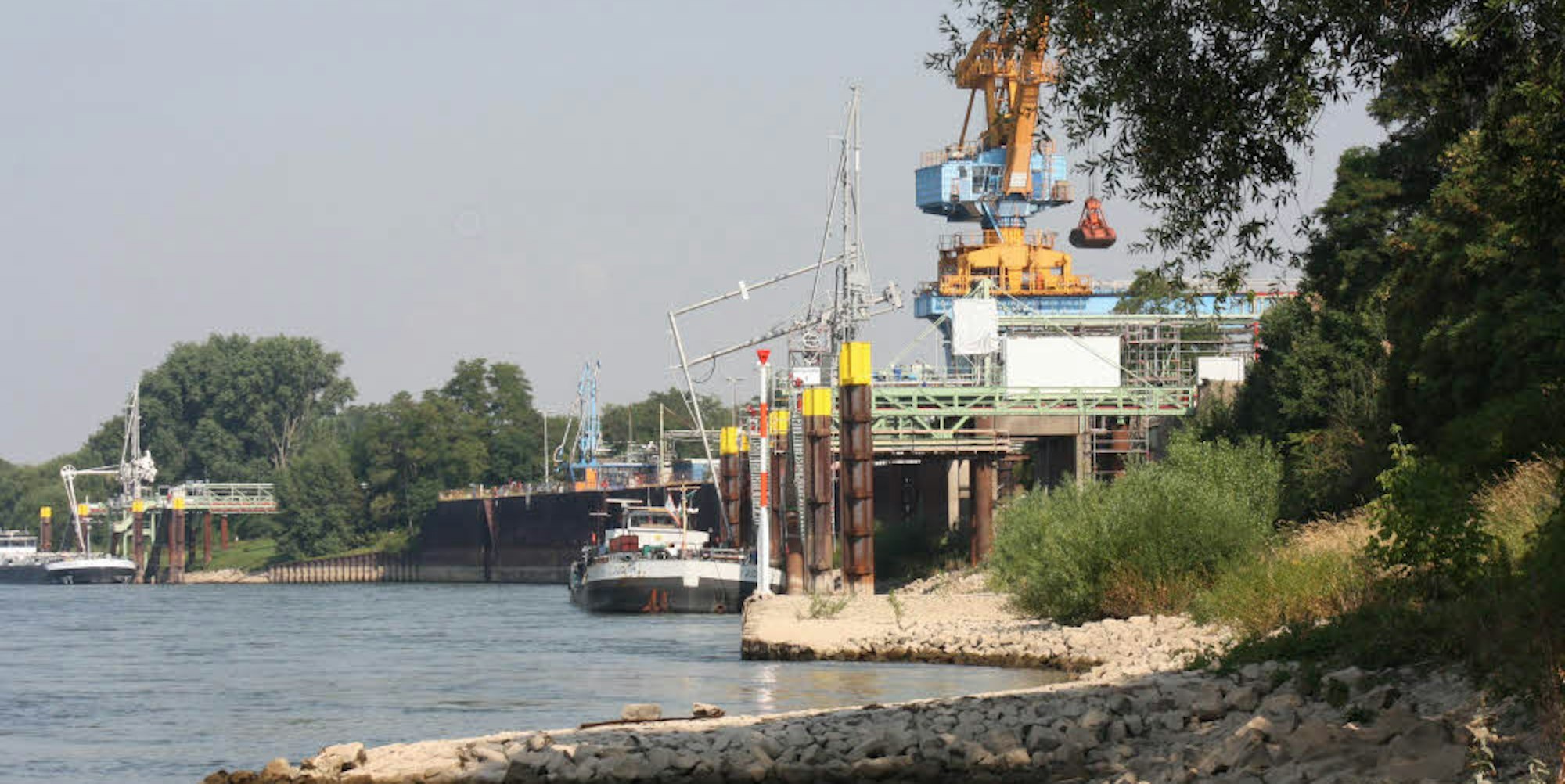 Die Tragkraft der alten Kaimauer des Lülsdorfer Hafens reicht nicht aus, um die Lasten des geplanten neuen Containerterminals zu tragen. Deshalb wird eine neue Hafenwand gebaut, die rund zwei Meter in den Fluss hinein ragt.