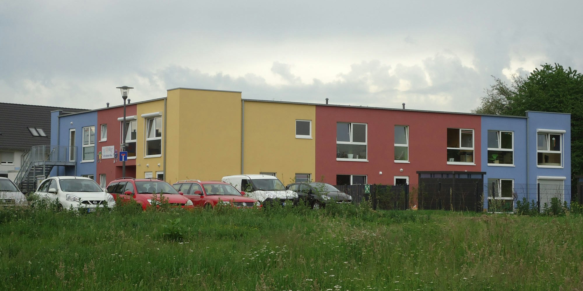 Auf der Wiese neben dem neuen Kindergarten in Niehl soll die Unterkunft entstehen. Auf der anderen Seite liegt ein Sportplatz.