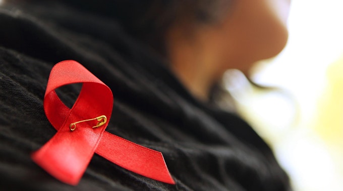 Eine Frau hat sich eine rote Aids-Schleife angesteckt