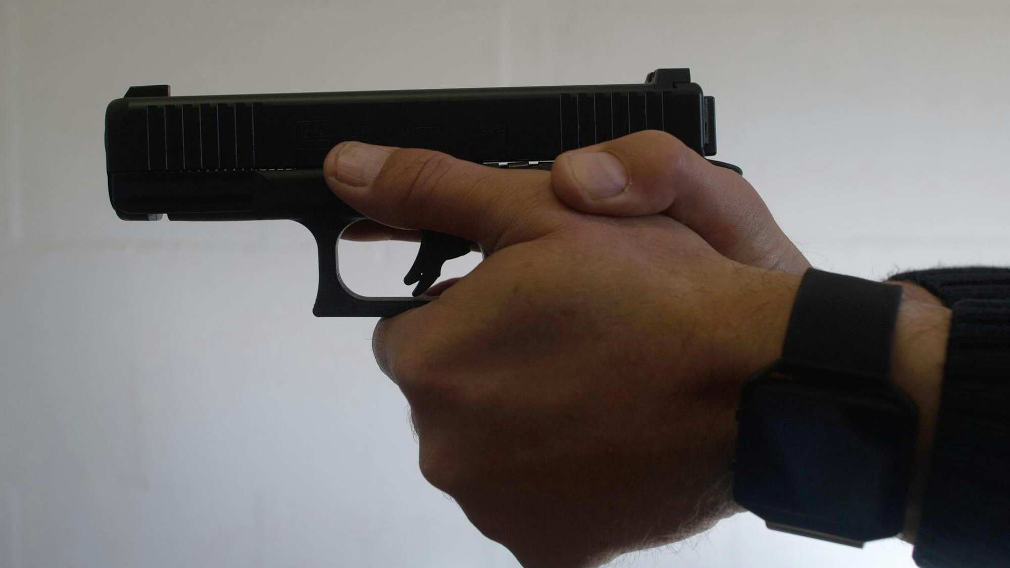 Ein Mann hält eine Pistole in beiden Händen.