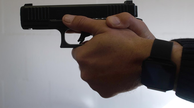 Ein Mann hält eine Pistole in beiden Händen.