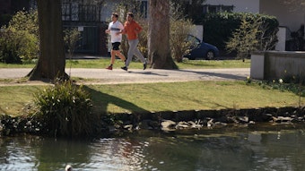 zwei Jogger auf einem Weg neben einem Kanal