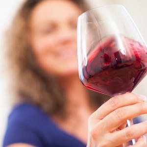 Frau hält ein Gas Rotwein in der Hand