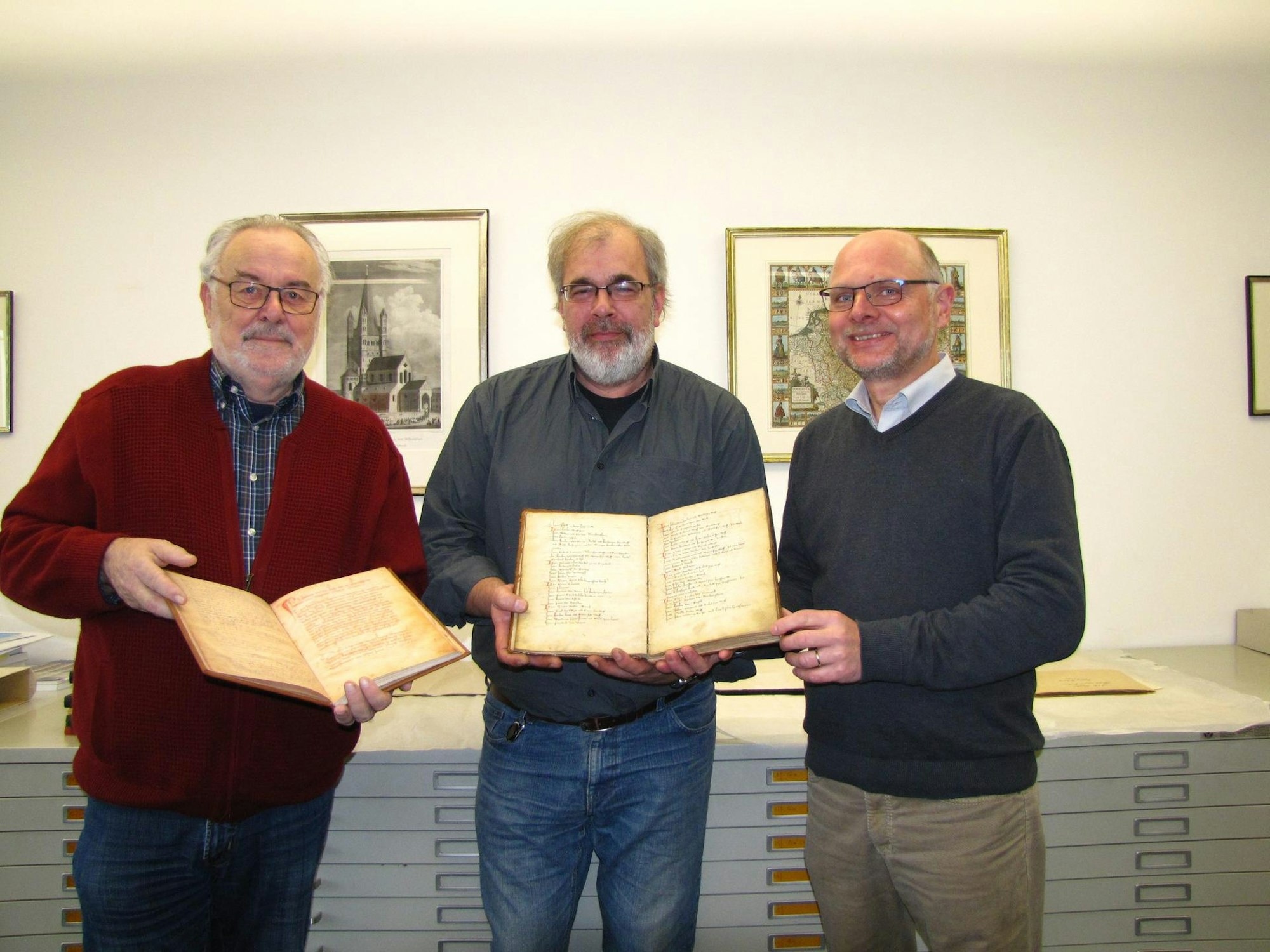 In der Kölner Diözesan- und Dombibliothek konnte Dieter Graf (l.) ein Faksimile des Bruderschaftsbuchs von 1429 aus den Händen von Bernd Schäfers (M.) und Dr. Harald Horst (r.) entgegennehmen.