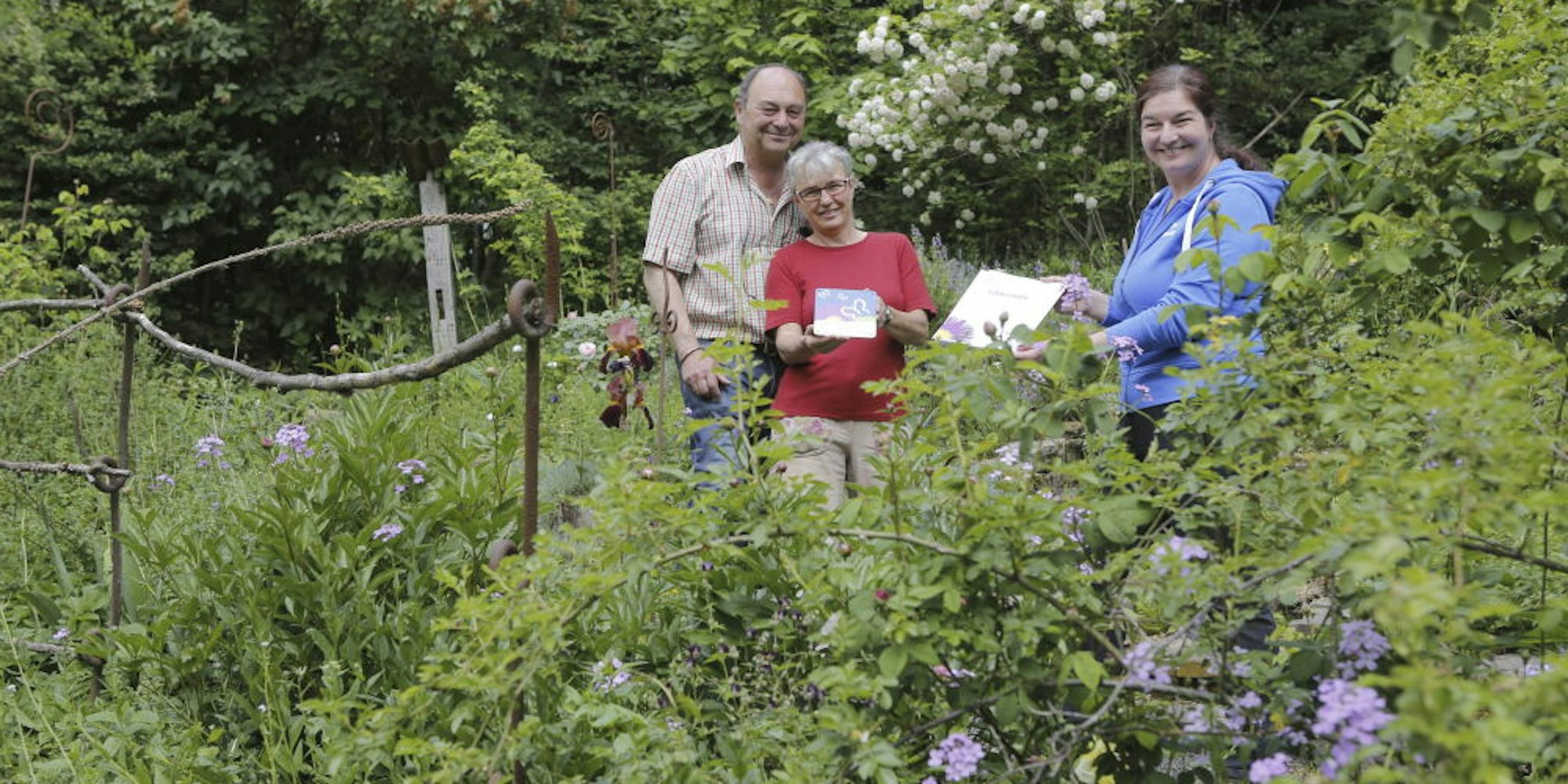 Die Auszeichnung überreicht Carola Hoppen (r.) an Katja und Klaus Wopfner in ihrem schmetterlingsfreundlichen Garten.