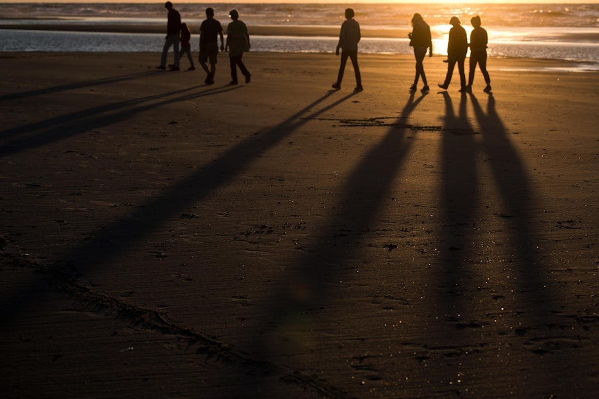 Spaziergänger bei Sonnenuntergang am Strand