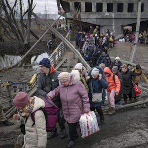 Bewohner benutzen einen Pfad unter einer zerstörten Straßenbrücke hindurch, um die umkämpfte Stadt nahe Kiew zu verlassen.