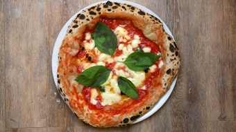 Eine Pizza Margherita liegt auf einem Teller und sieht appetitlich aus.