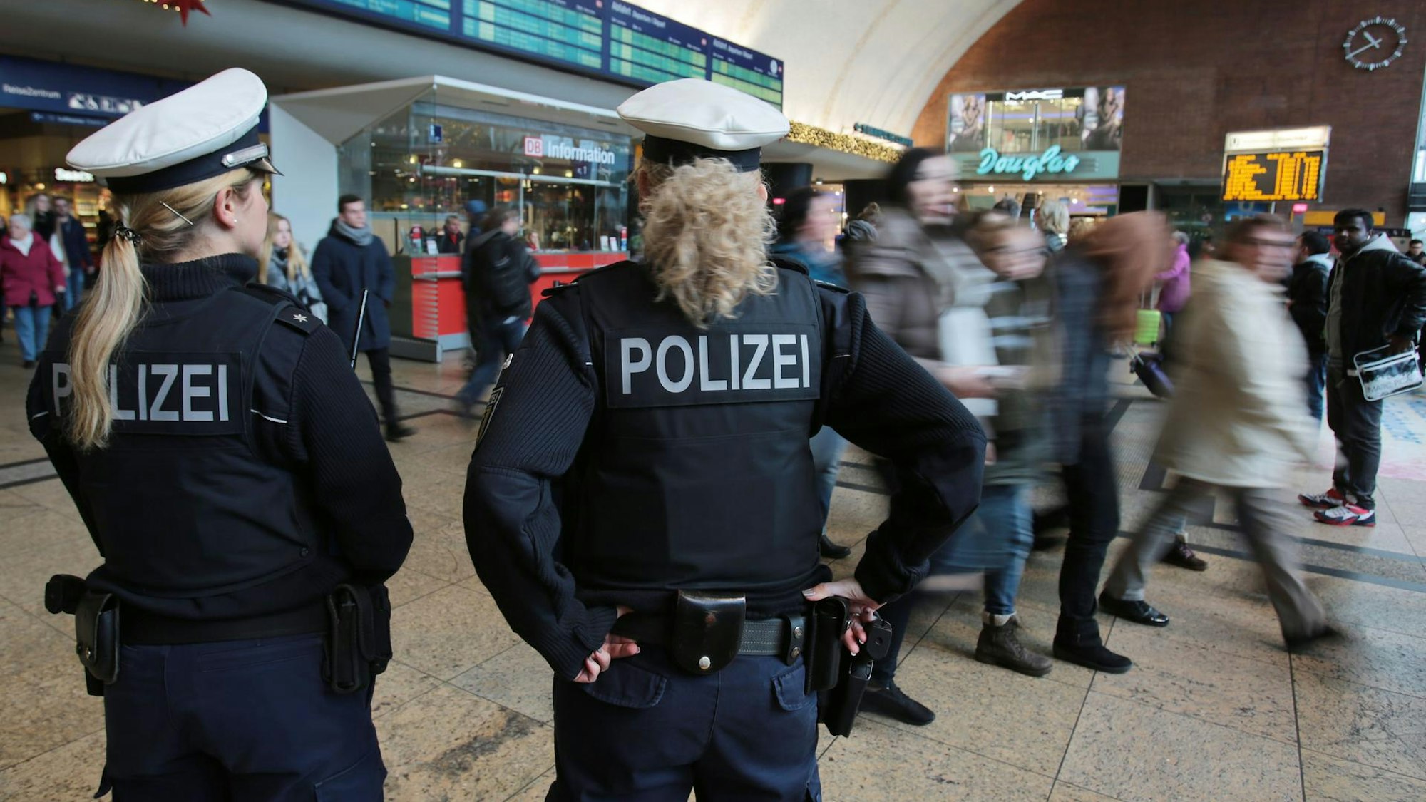 Zwei Polizistinnen kontrollieren im Kölner Hauptbahnhof Menschen.
