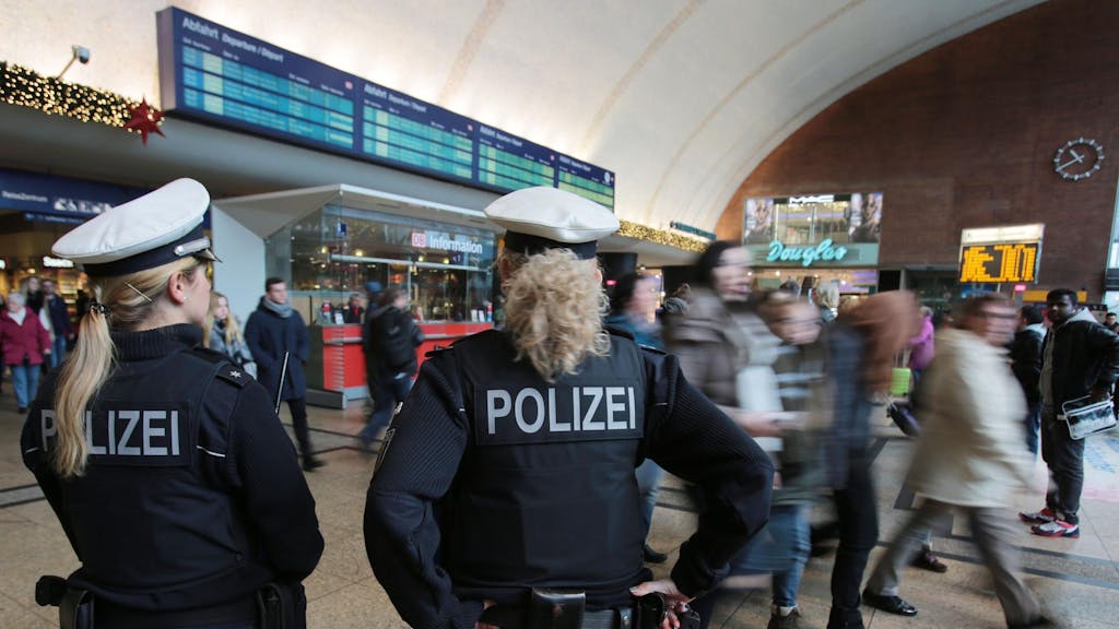 Zwei Polizistinnen kontrollieren im Kölner Hauptbahnhof Menschen.