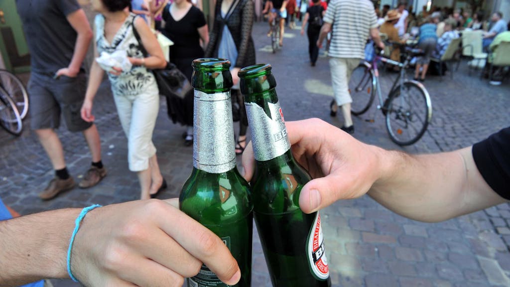 Zwei Menschen stoßen mit Bierflaschen an (1)