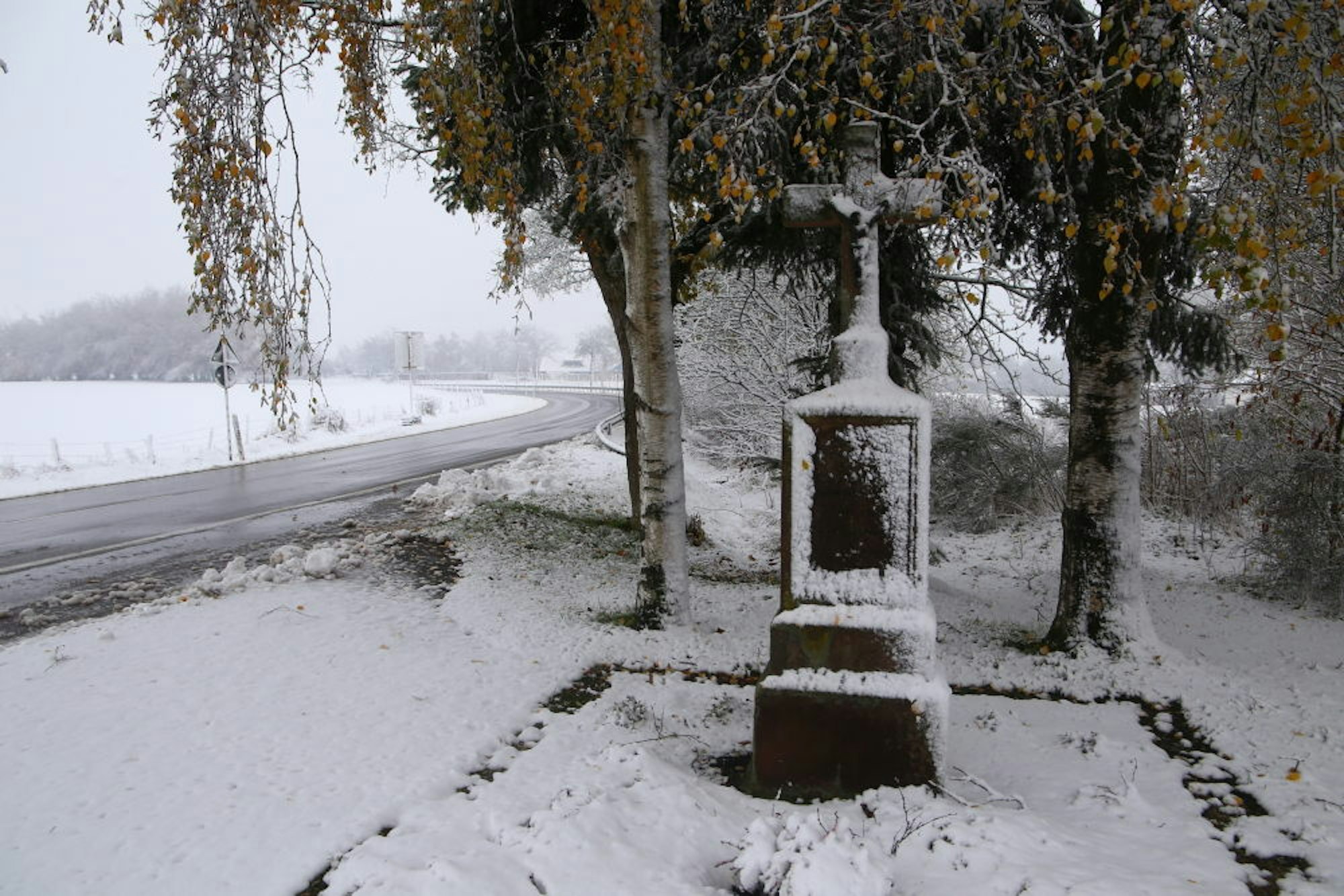 Mit Schneehauben bedeckt: Ein Wegekreuz an einer Landstraße in der Gemeinde Hellenthal.