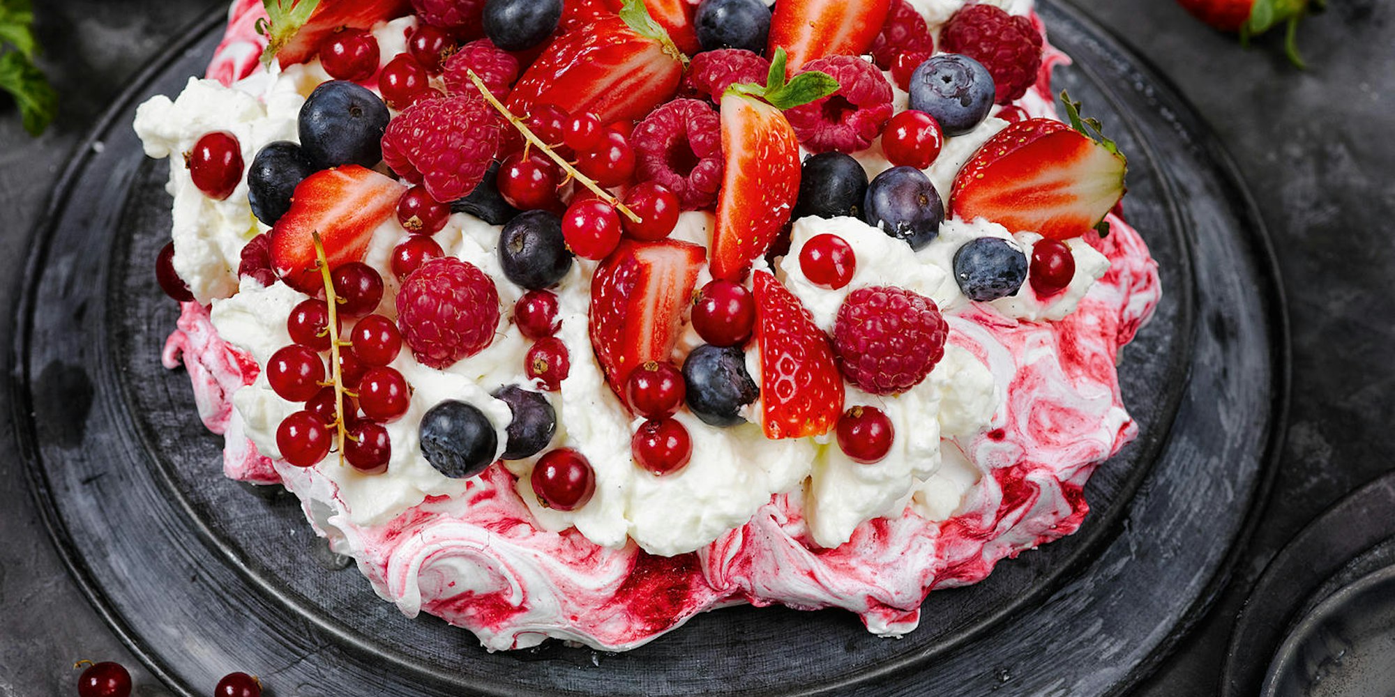 Pavlova-Torte mit Erdbeeren, Himbeeren, Johannisbeeren und Blaubeeren