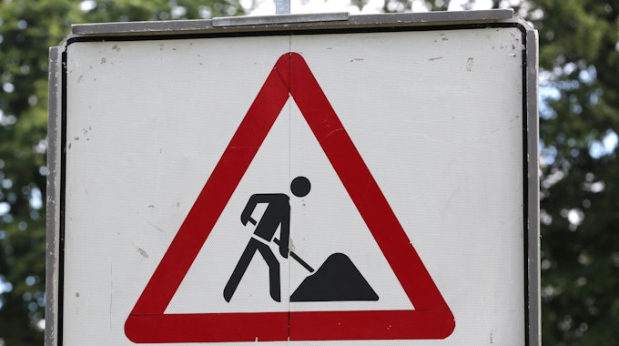 Ein Schild warnt vor Bauarbeiten in einem Park.