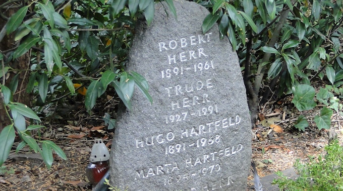Trude Herrs Grabstein (l.); Günter Leitner (Mitte) konnte seinen Zuhörern viel Wissenswertes über den Friedhof vermitteln.