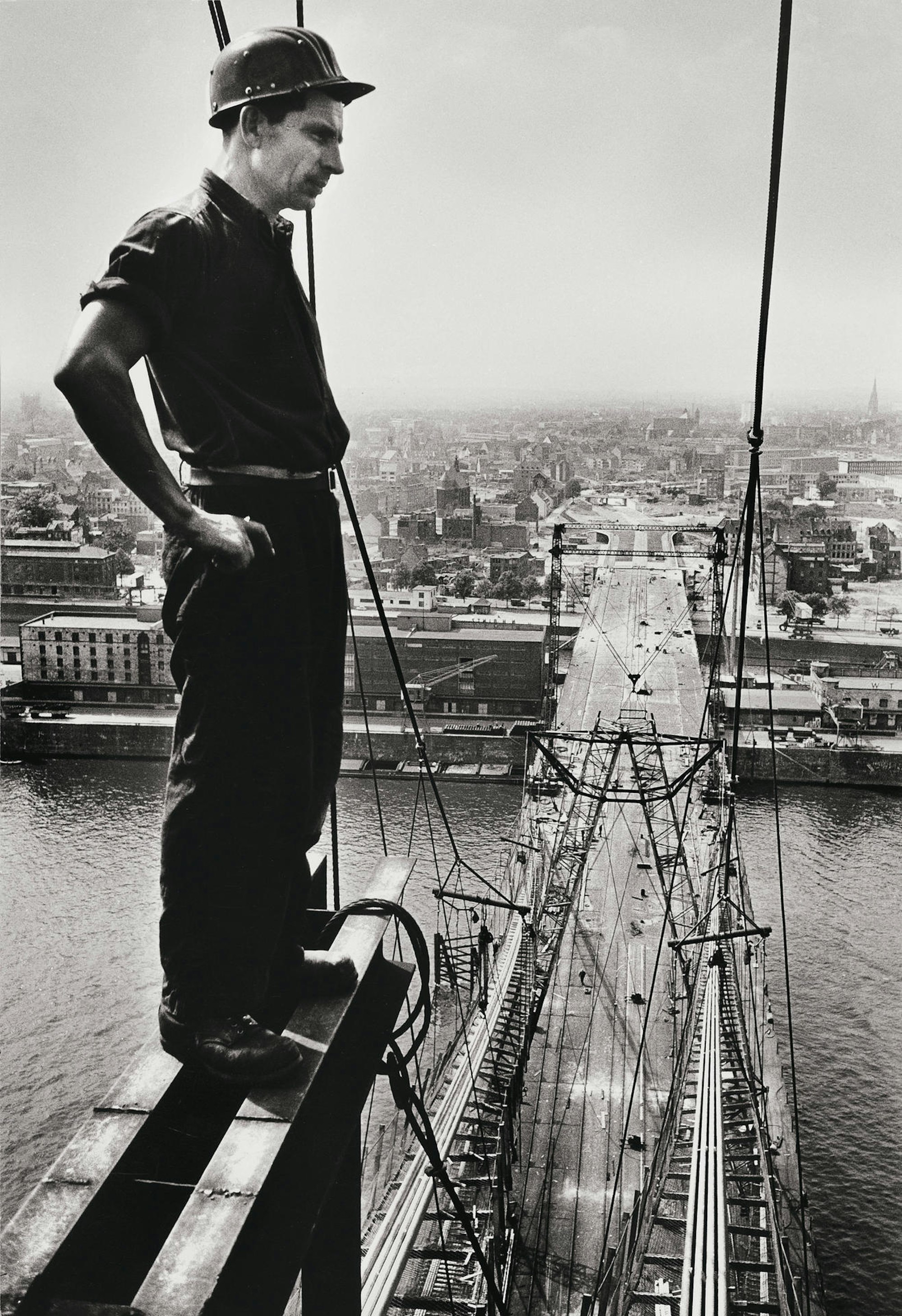 1958: Ein Arbeiter blickt vom 77 Meter hohen Pylon auf die Brückenbaustelle hinab.